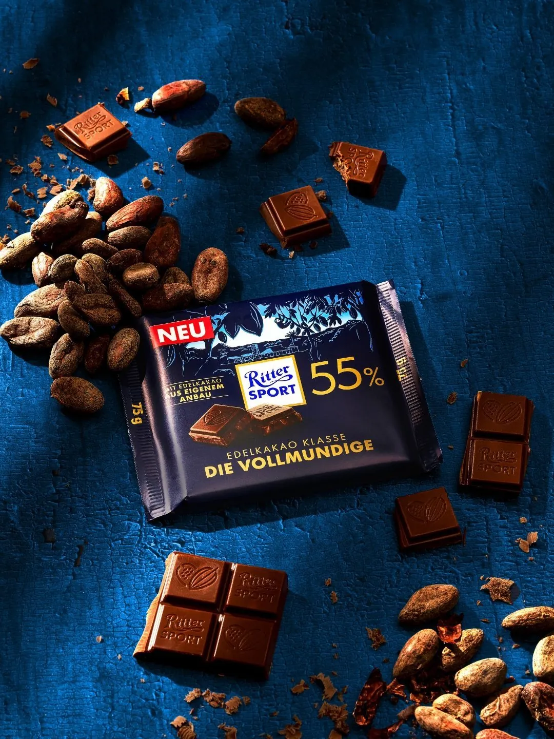 Ritter Sport Edelkakao-Klasse auf blauem Grund mit Kakaobohnen